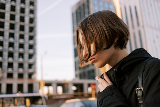 Woman Stands in Urban Setting Under Sunset Sky