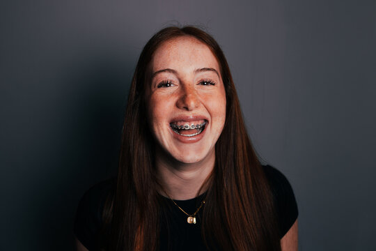 Smiling teenage girl portrait with braces on gray background