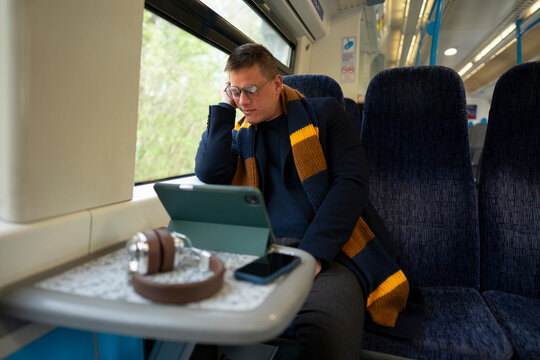Tired commuter sleeping beside tablet on train