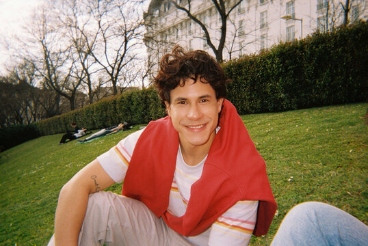Man smiling while sitting on grass in city park