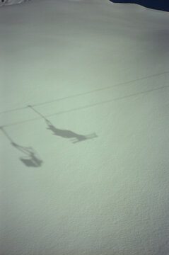 Shadow of a chairlift on snow at a ski resort.