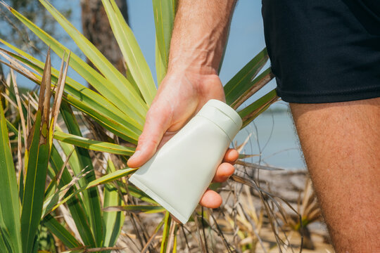Holding sunscreen lotion bottle beach