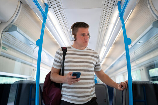 Young man commuting by train with smartphone