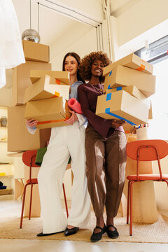 Teamwork portrait of women carrying boxes in office