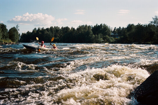 Kayakers move through rough waters in summer