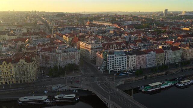 Aerial drone view of the riverfront district with a tram intersection, ornate historic buildings and church spires at sunrise.