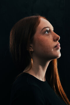 Teen girl profile portrait looking up in dark studio light
