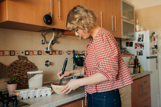 Woman whisking ingredients in bowl in home kitchen