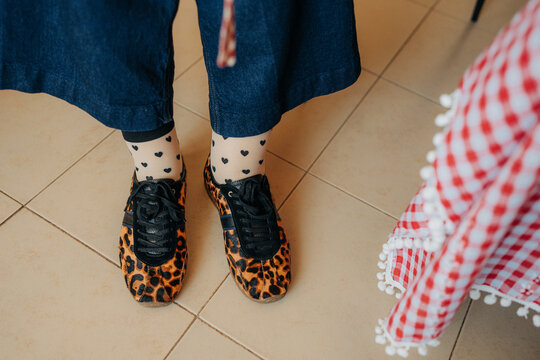 Stylish leopard print shoes with patterned socks on kitchen floo