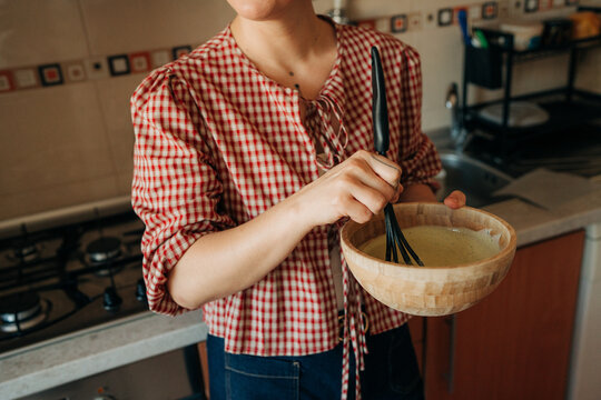 Anonymous woman whisking batter in wooden bowl