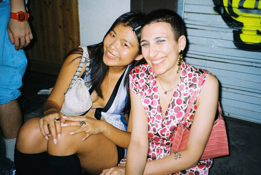 Two women smiling together at night, candid film portrait
