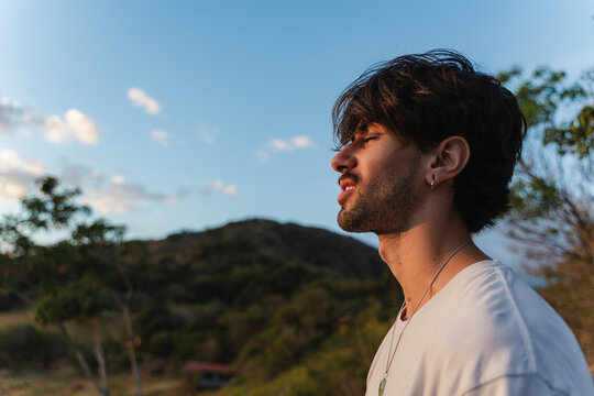 Young man meditating eyes closed finding peace outdoors