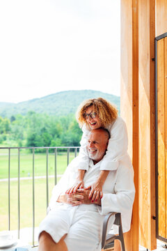Senior Couple in Bathrobe Hugging on Balcony
