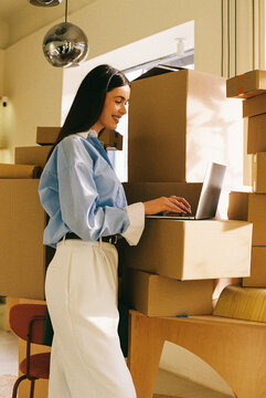 Woman using laptop among boxes film photo