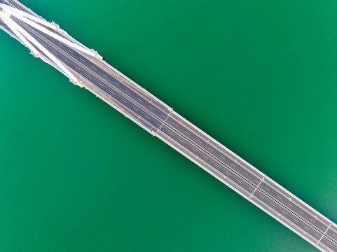 Top Down Aerial View of Bridge Spanning Green Water
