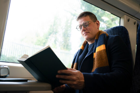 Man reading book during train commute