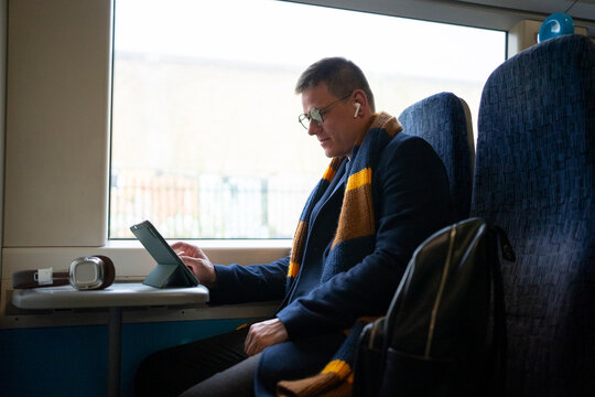Man reading book by window in train