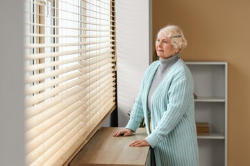 Thoughtful senior woman near window at home