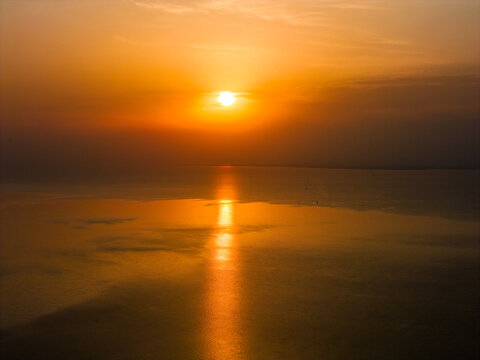 Golden sunset over calm lake with tree silhouettes on shoreline