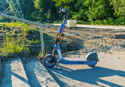 Electric scooter parked on sunlit roadside near construction site