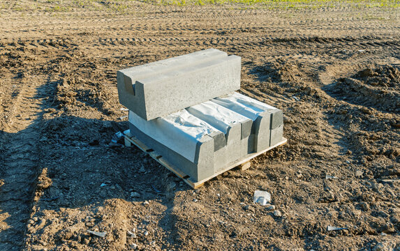 Concrete curb blocks stacked on wooden pallet at construction site