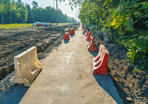 Pedestrian pathway under construction with safety barriers along wooded roadside