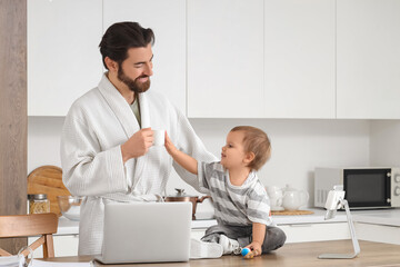 Obraz premium Working father with coffee and his little baby during parental leave in kitchen