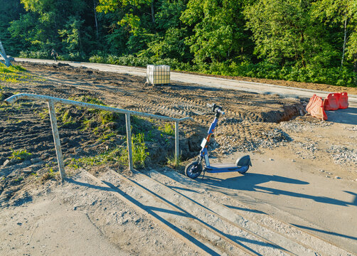 Electric scooter parked by construction site near wooded area