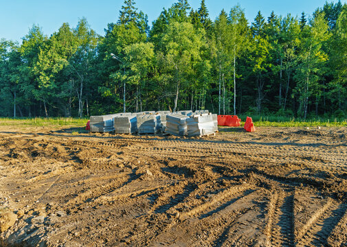 Construction site clearing with stacked concrete blocks and forest edge
