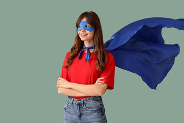 Beautiful young woman in superhero costume on blue background © Pixel-Shot