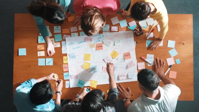 Top view of project manager writing and sticking stick notes. Aerial view of professional business people working together planning strategy while drafting mind mapping at meeting room. Symposium.