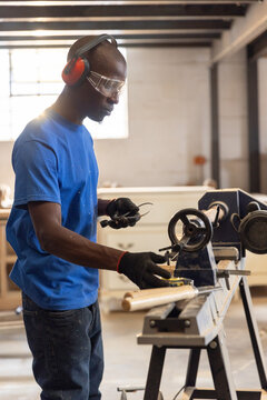 Wood lathe shaping wooden spindle with chisel in carpentry workshop near large window