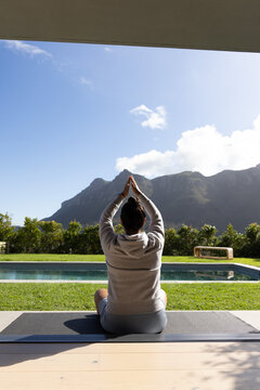 Yoga mat is resting on wooden patio beside rectangular pool, mountains rising beyond