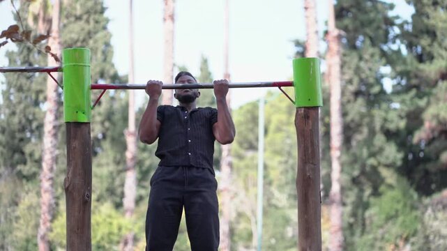 Black Latino Man Performing Pull Up Exercise in Outdoor Park