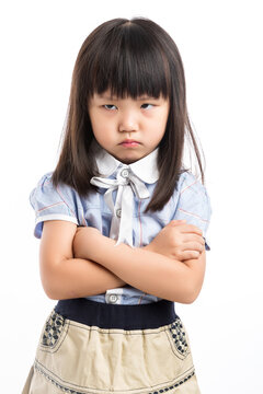 Upset and grumpy Asian girl with arms crossed, looking at camera with angry eyes.