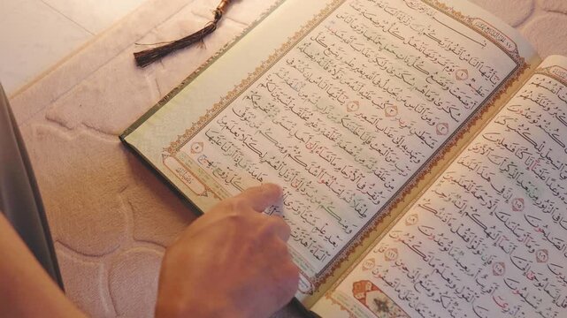 Close-up of a hand following Quranic text while reading the Holy Quran. Islamic learning, spiritual reflection, religious devotion, sacred scripture study and faith-inspired lifestyle concept.