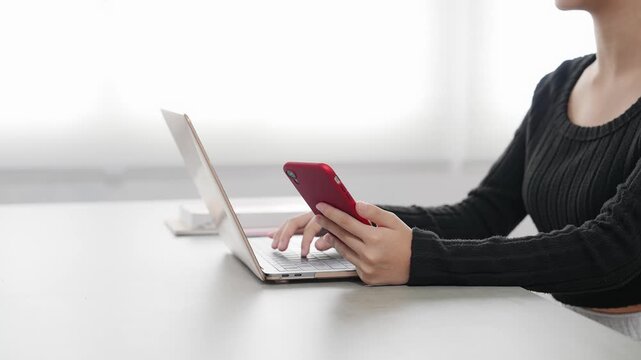 A woman working using a laptop and a smartphone.