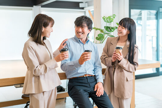 Businessmen and businesswomen chatting while drinking coffee in the office.