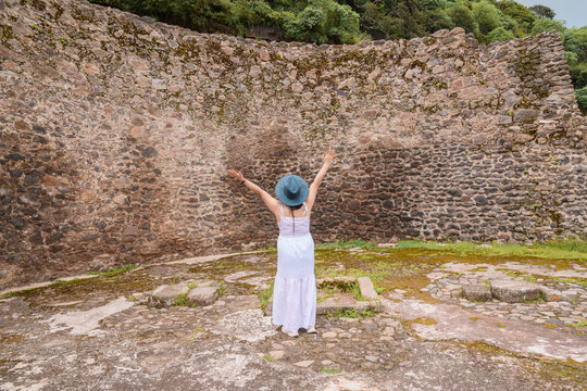 Woman Standing with Arms Raised by Ancient Stone Wall in Malinalco