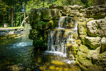 Scenic waterfalls and cascades within Confederation Park in Stratford, Ontario, creating a tranquil natural feature surrounded by lush greenery and historic park landscaping. © Mehdi