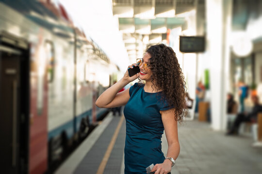 Closeup shot of beautiful curly hair young business woman talking on the phone and the train station