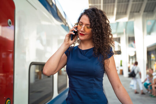 Closeup shot of beautiful curly hair young business woman talking on the phone and the train station