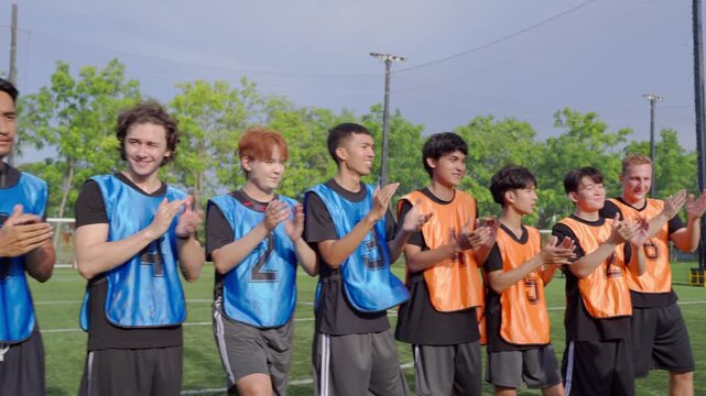 Two teams of diverse male football players standing and clapping hands. 