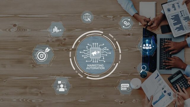 This stock image showcases the concept of marketing automation, featuring digital icons and hands engaged in business tasks on a wooden table, reflecting collaboration and innovation. Raster