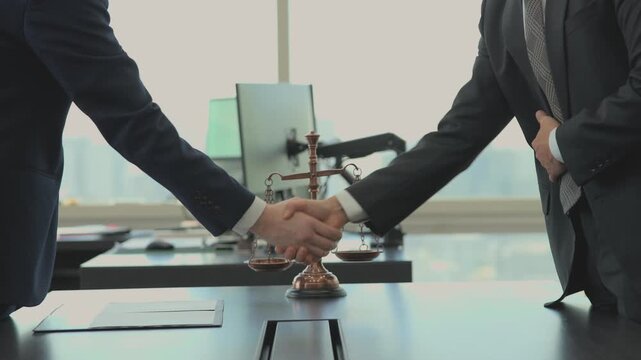 Business professionals or lawyers shaking hands over a scale of justice, symbolizing legal agreement, partnership, and fairness in a corporate office setting.