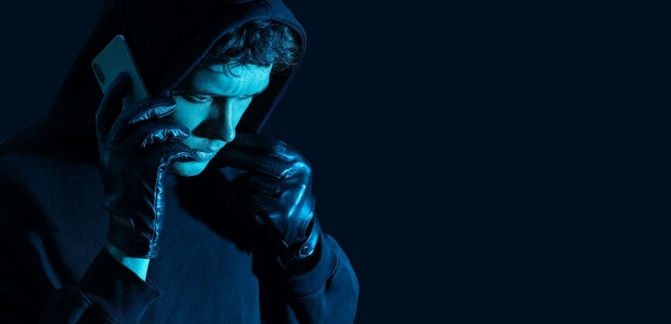 Cybercrime and data theft with hacker in hoodie using smartphone for illegal activities, digital security risks and online fraud