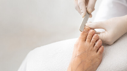 Fototapeta premium Professional Pedicure Session Expert Hands Carefully Filing Toenails for Ultimate Foot Grooming and Relaxation