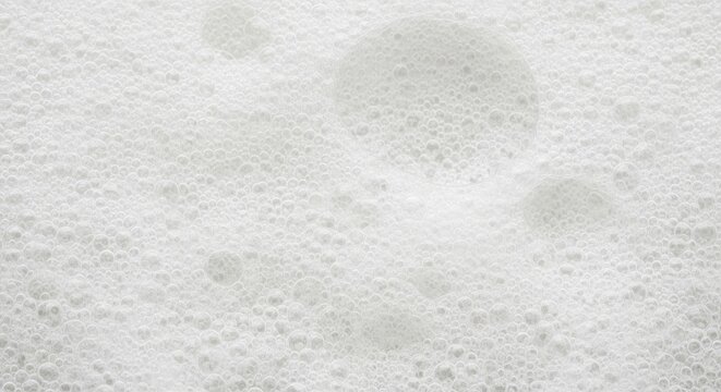 A close-up shot of a white, foamy surface with numerous bubbles. The bubbles are of varying sizes and create a textured, almost lunar-like pattern.