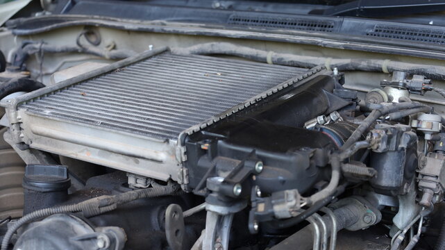 Old intercooler. A dirty intercooler with engine oil stains installed on a diesel engine during repairs in a garage. Car maintenance concept with copy space with selective focus.