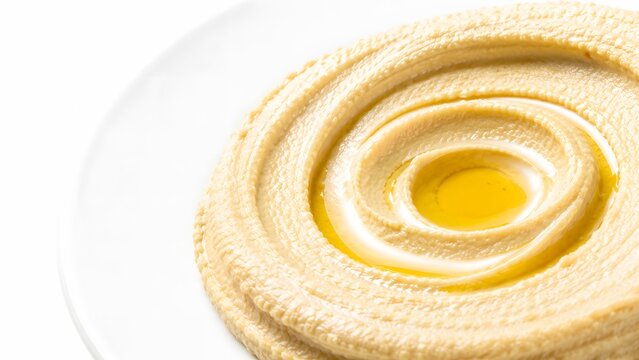 Creamy classic chickpea hummus dip with olive oil swirl served on a clean white plate closeup